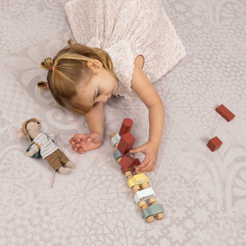Child playing with wooden blocks on the Toddlekind Aria Maple Playmat, featuring a soft neutral jacquard pattern