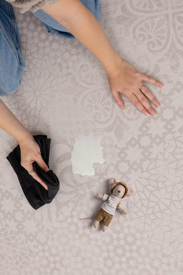 Close-up of the Toddlekind Aria Playmat  Maple with a spill being wiped clean, highlighting its easy-to-clean surface.