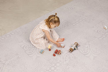 Child playing with wooden toys and a mouse plush toy in the aria maple haven playmat