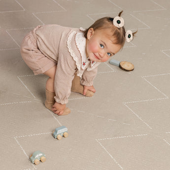 toddler playing with toy cars on the cushioned haven mat tulum desert caliza