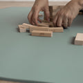 Hands arranging wooden blocks on a green Evo Mat