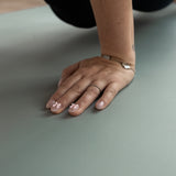 Hand with decorative nail art on a green Evo Mat