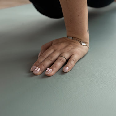 Hand with decorative nail art on a green Evo Mat