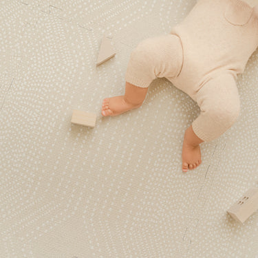 Close-up of baby legs and wooden blocks on toddlekind baby toddler foam modern designer puzzle play mat haven deco ecru.