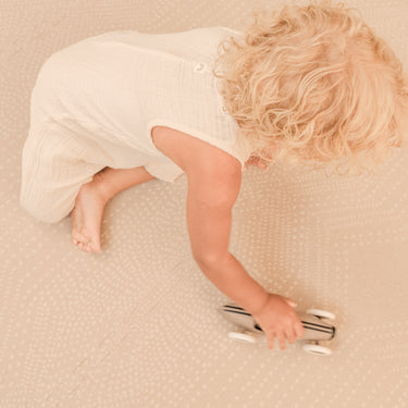 Toddler crawling and pushing a toy car across the toddlekind baby toddler foam modern designer puzzle play mat haven deco latte.