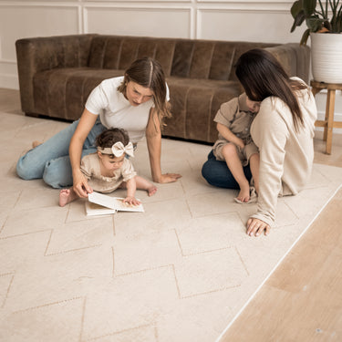 Two mothers sitting with babies reading and playing together on the toddlekind baby toddler foam modern designer puzzle play mat haven tulum bone.