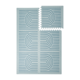 Interlocking tiles arranged in a grid with one piece lifted showing the toddlekind baby toddler foam modern designer puzzle play mat haven linear mineral.