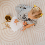 Overhead view of baby toddler drawing with crayons and basket on the toddlekind baby toddler foam modern designer puzzle play mat haven linear linen.