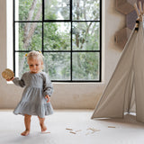 Baby toddler walking barefoot holding a toy in a sunlit room on the toddlekind baby toddler foam modern designer puzzle play mat haven linear linen.
