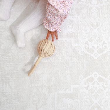 Close-up of toddler hand reaching for a toy on the textured surface of the toddlekind baby toddler foam modern designer puzzle play mat haven parisa millet.