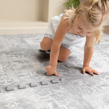 Toddler crawling and playing on soft patterned foam surface, showing comfort and safety of the toddlekind baby toddler foam modern designer puzzle play mat haven parisa pearl blue.