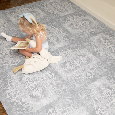 Overhead view of child sitting and reading on a large assembled foam mat, showcasing full coverage of the toddlekind baby toddler foam modern designer puzzle play mat haven parisa pearl blue